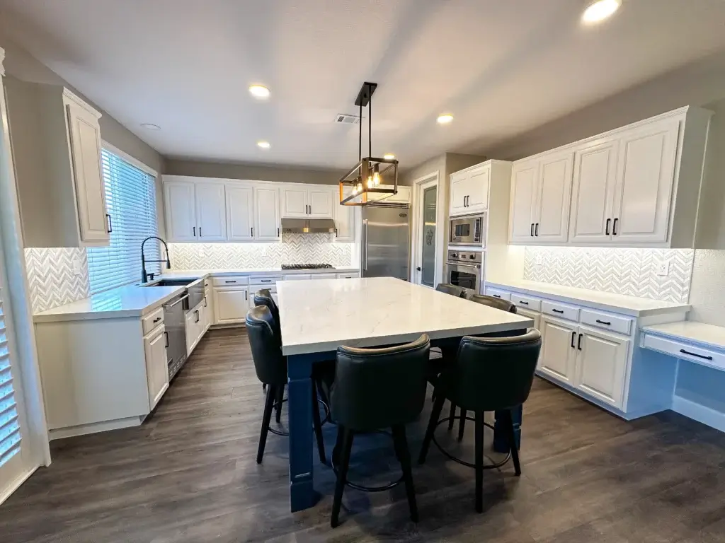 Walnut Creek 69 Modern kitchen with white cabinets, marble island, black chairs, stainless steel appliances, and sleek flooring.